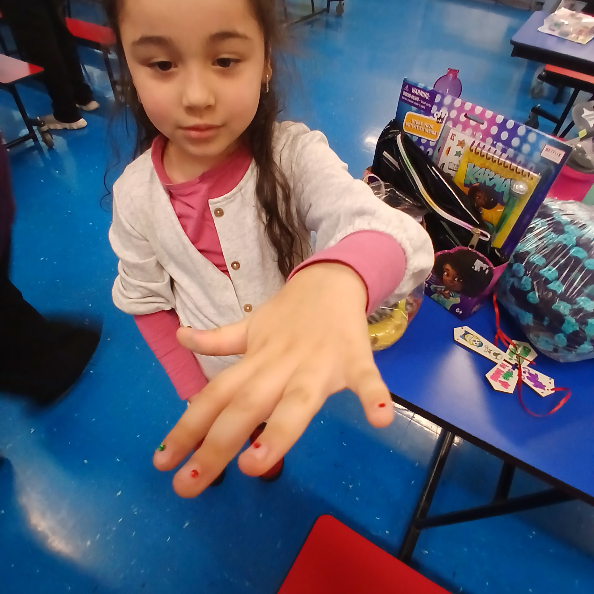 Child showing painted nails and activity supplies during the event