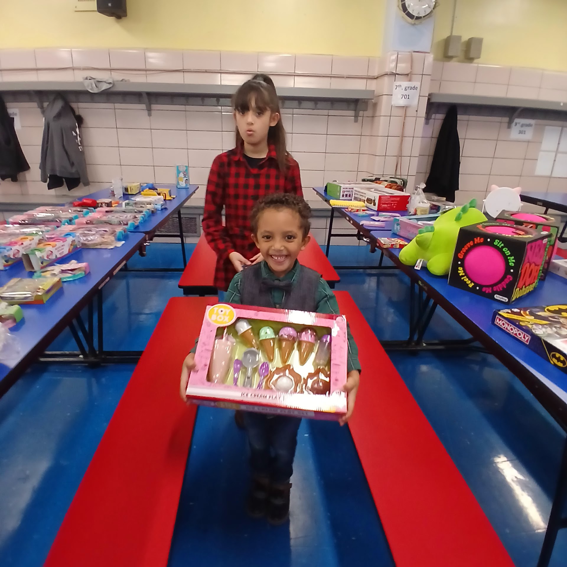 Child proudly carrying an ice cream toy set through the event room