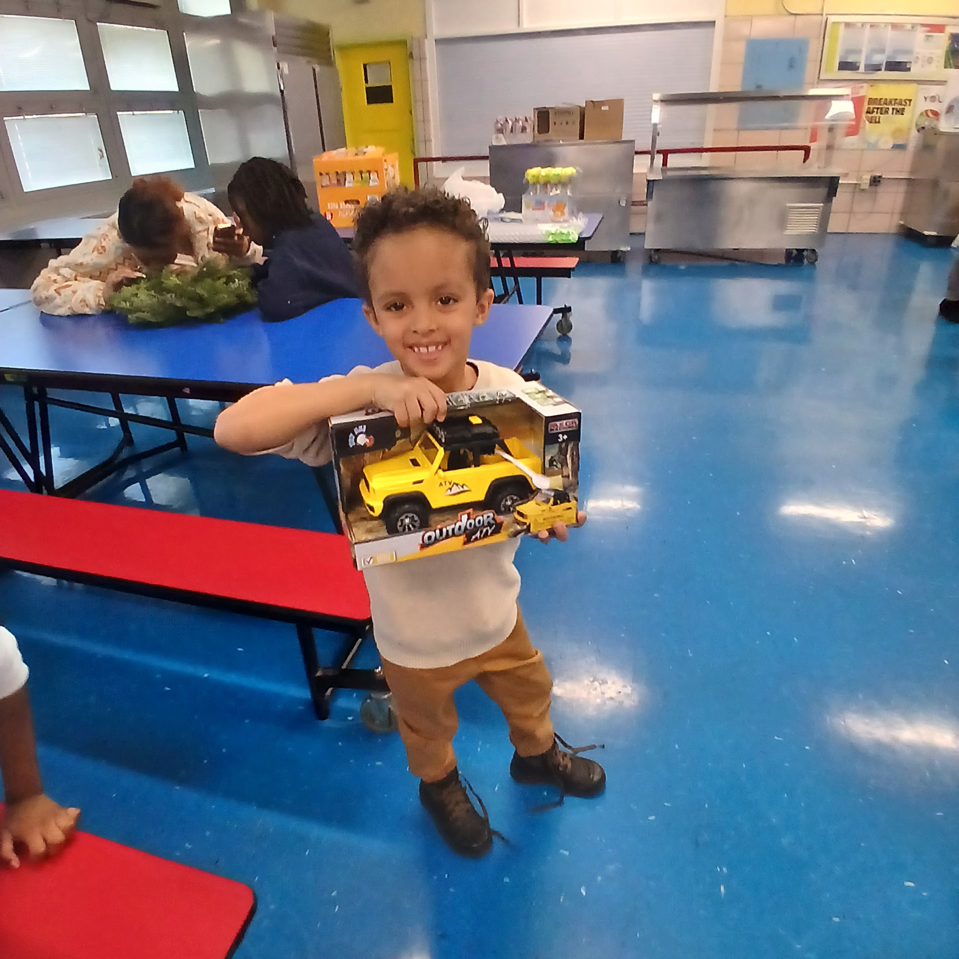Young child smiling and holding a toy truck at the gift event